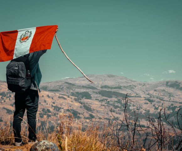 A person holding up the flag of Peru.