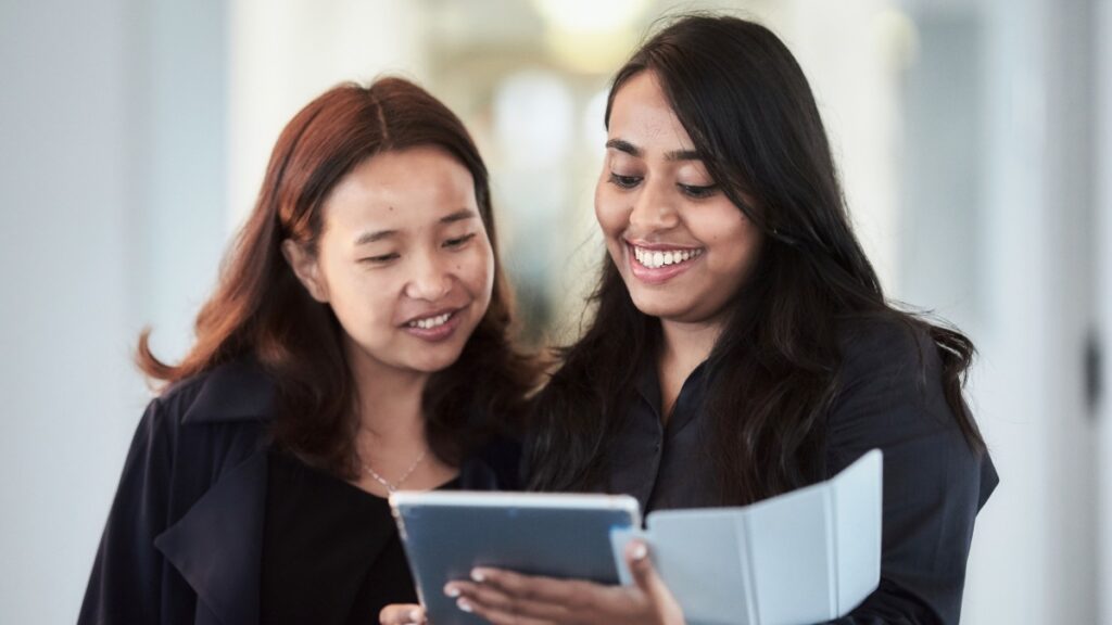 Two female mba students from hhl smiling and holding an ipad.