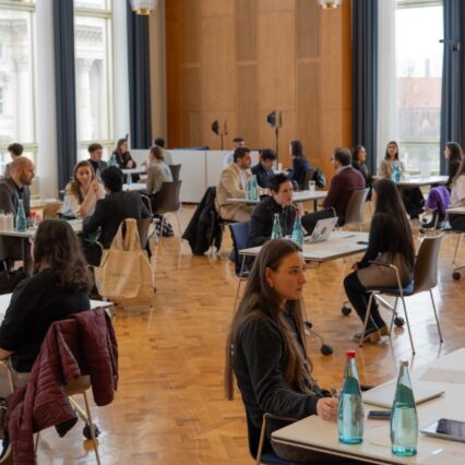 The picrure shows a room with many tables at each of which are two people talking.