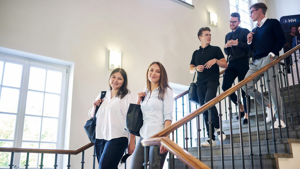 HHL students going down a staircase, talking with each other.