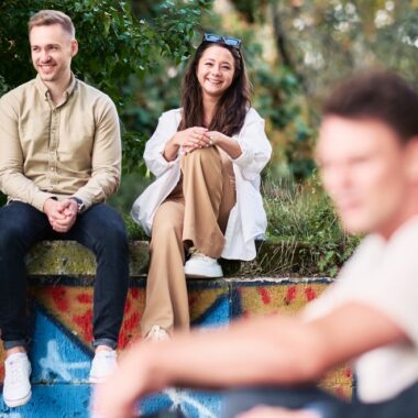 A group of HHL students outside the campus, in the green, sitting on a stone wall.