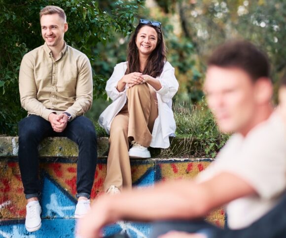 A group of HHL students outside the campus, in the green, sitting on a stone wall.