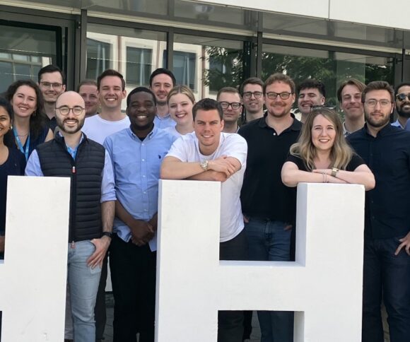 Eine große Gruppe von Promotionsstudierenden der HHL aus der ganzen Welt, alle lächeln.