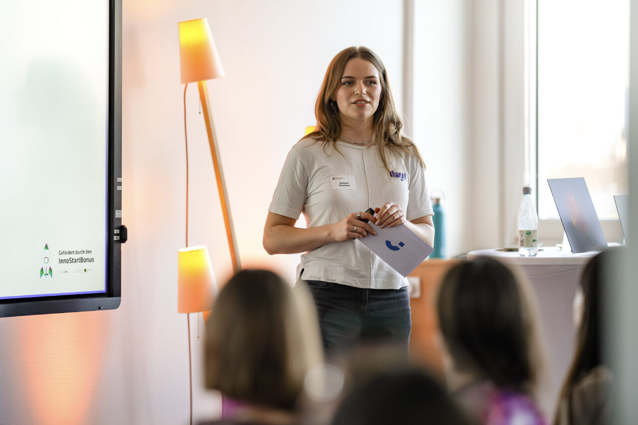 Women speaks in front of the panel at EmpowerHER