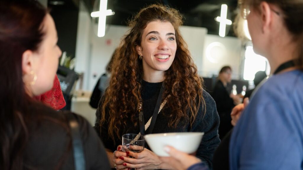 The photo shows three women networking at an event