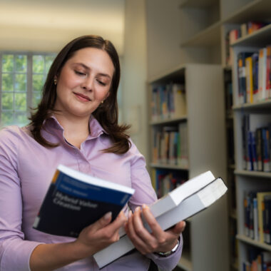Studentin hält Buch in der Hand.