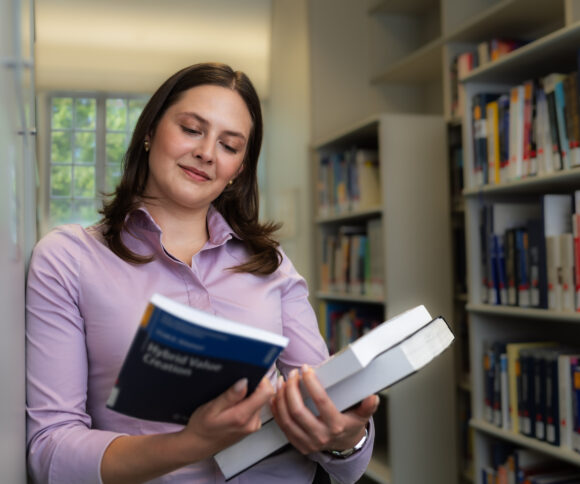 Studentin hält Buch in der Hand.
